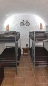 a room with three bunk beds and a bike on the wall at CASA CUEVA LOS HONORIOS in Cortes de Baza