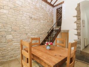 a wooden table with two chairs and a stone wall at Walton House in Matlock