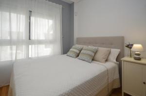 Un dormitorio con una cama blanca con almohadas y una ventana en Apartamento zona exclusiva garaje gratis y Netflix, en Vigo