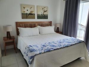 a bedroom with a bed with a blue and white blanket at Casa Duplex Aconchegante de Frente para o Mar in Porto Seguro