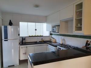 uma cozinha com armários brancos e um frigorífico branco em Casa Duplex Aconchegante de Frente para o Mar em Porto Seguro
