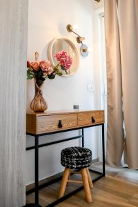 een tafel met een vaas met bloemen en een spiegel bij Residence by Georgia Studios in Fira