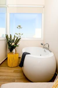 een badkamer met een groot wit bad voor een raam bij Residence by Georgia Studios in Fira
