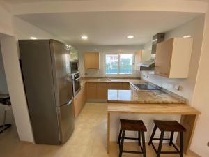 a kitchen with a stainless steel refrigerator and two bar stools at Villa Tranquila in Alcossebre
