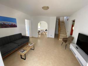 ein Wohnzimmer mit einem Sofa, einem TV und einem Tisch in der Unterkunft Villa Tranquila in Alcossebre