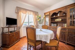 a dining room with a table and chairs and a television at Casa Fernandes in Burgau
