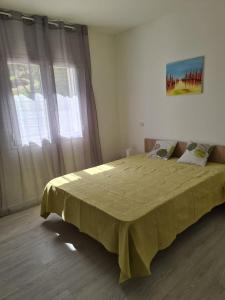 a bedroom with a bed with a yellow blanket on it at Logement 45 m2 vue mer in San-Martino-di-Lota