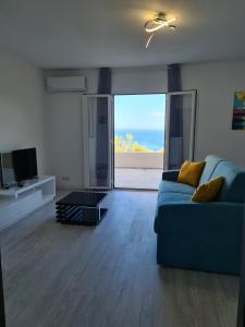 a living room with a blue couch and a television at Logement 45 m2 vue mer in San-Martino-di-Lota