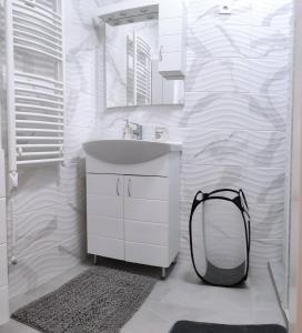 biała łazienka z umywalką i lustrem w obiekcie Sára Apartman Nyíregyháza w Nyíregyházie