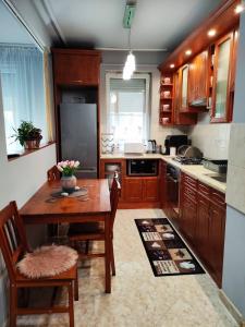 una cocina con armarios de madera y una mesa y sillas de madera. en Sára Apartman Nyíregyháza, en Nyíregyháza