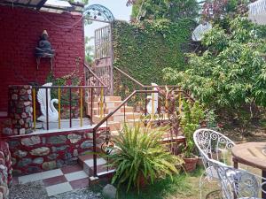 Oxygen Homestay في دهرادون: حديقة فيها درج وكراسي وجدار من الطوب