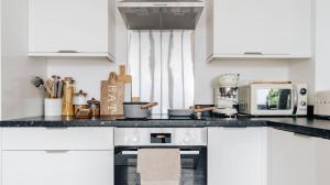 a kitchen with white cabinets and a black counter top at BRAND NEW apartment - Stay in the heart of the city in Norwich