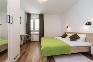 a bedroom with a bed with a green blanket on it at Saluto al Sole in Zadar
