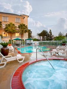 a large swimming pool with chairs and a hotel at Ayres Hotel Anaheim in Anaheim