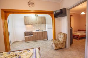 a living room with a kitchen and a chair and a room at Lola Rooms in Nea Vrasna