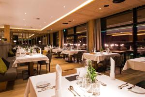 un restaurante con mesas y sillas blancas y ventanas en Sportresidenz Zillertal - 4 Sterne Superior, en Uderns
