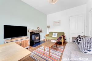 uma sala de estar com um sofá, uma televisão e uma lareira em Cozy with Character Cochrane Cottage at Leith Links Park em Edinburgo