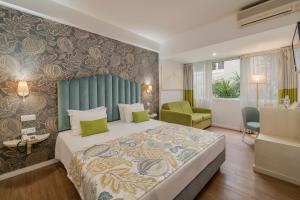 a bedroom with a large bed and a green headboard at Hotel Madeira in Funchal
