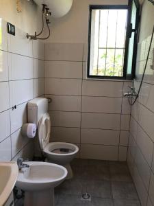 uma casa de banho com um WC, um lavatório e uma janela em Fati Guest House em Durrës