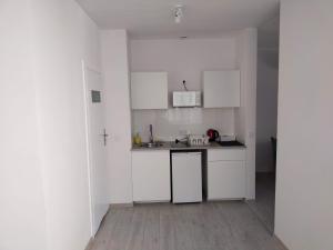 a small kitchen with white cabinets and a wooden floor at Center Warsaw- Apartamenty Smolna in Warsaw