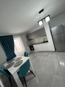 a kitchen with a white table and blue chairs at Borșa ApartHotel 4 in Borşa