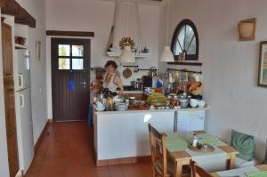 a woman standing in a kitchen with a table at Cortijo el Campillo in Los Albaricoques