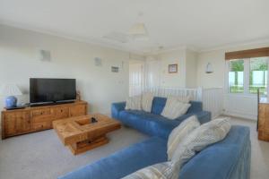 a living room with a blue couch and a tv at 4 Coram Court in Lyme Regis
