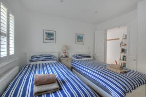 two beds in a room with blue and white stripes at Starfish in Lyme Regis