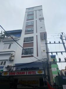 a tall white building with a sign in front of it at Khách sạn Sông Chanh 3 Cát Bà in Cat Ba