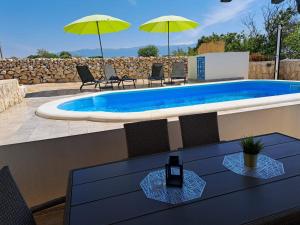 Una piscina con sillas y sombrillas en un patio. en Villa Venkin Dvor, en Novalja
