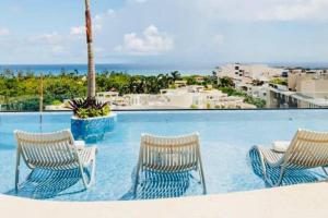 a swimming pool with two chairs and the ocean at LOFT VIEW SEA The best ubication at 5th AV in Playa del Carmen