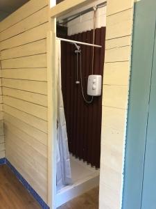 a bathroom with a shower in a wooden wall at The Tawny Shepherd Hut, Whitehouse Farm in Stowmarket