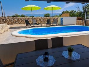 a pool with chairs and umbrellas on a patio at Villa Venkin Dvor in Novalja