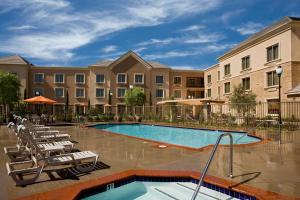 a swimming pool with chairs and a building at Ayres Hotel Chino Hills - Ontario in Chino Hills