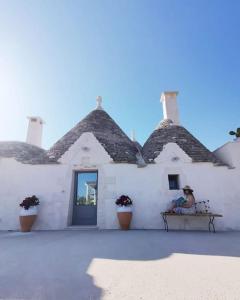a man sitting on a bench in front of a white building at Trullo La chicca della valle in Cisternino