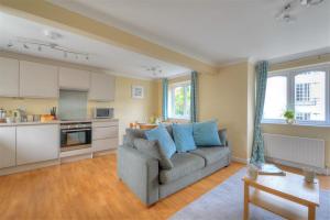 Una sala de estar con un sofá y una cocina. en The Old Bakehouse, en Lyme Regis
