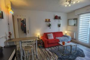 a living room with a red couch and a table at Cosy T1bis proche CentreVille, Petit Port, Audencia in Nantes