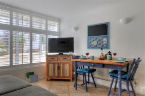 a room with a desk with a television and a table with chairs at Waterloo Place in Charmouth