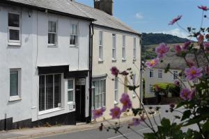 a white building with purple flowers in front of it at Waterloo Place in Charmouth