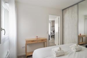 a bedroom with a bed and a table and a mirror at Beautiful flat 100m to the sea in La Rochelle - Welkeys in La Rochelle