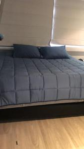 łóżko z niebieskimi poduszkami w pokoju w obiekcie Habitación Deluxe w mieście Bogota