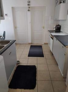 eine Küche mit weißen Schränken und schwarzen Arbeitsplatten in der Unterkunft Reni Apartman in Siófok