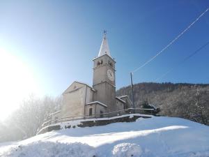 una iglesia con una torre de reloj en la nieve en LOCAZIONE TURISTICA CASA CITTADELLA, en Arten