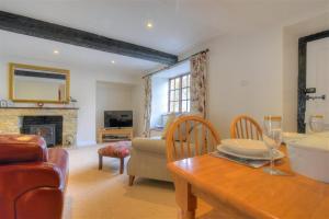 een woonkamer met een bank, een tafel en een open haard bij Foxley Cottage in Charmouth