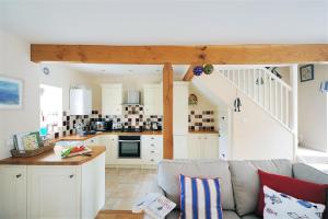 een woonkamer met een bank en een keuken bij Half Moon Cottage in Lyme Regis