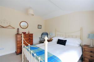 een slaapkamer met een wit bed en een dressoir bij Half Moon Cottage in Lyme Regis