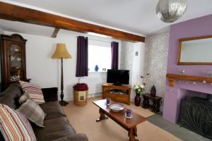 a living room with a couch and a tv at Sunnyside in Colyton