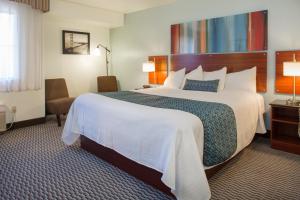 a hotel room with a large bed and a chair at Hotel Mira Vista in El Cerrito