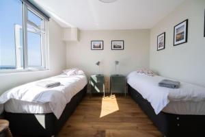 2 Betten in einem Zimmer mit 2 Fenstern in der Unterkunft 2 Beach Way House in Lyme Regis