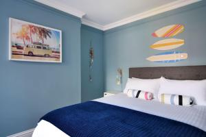 um quarto com paredes azuis e uma cama com almofadas listradas em Breakwater em Seaton